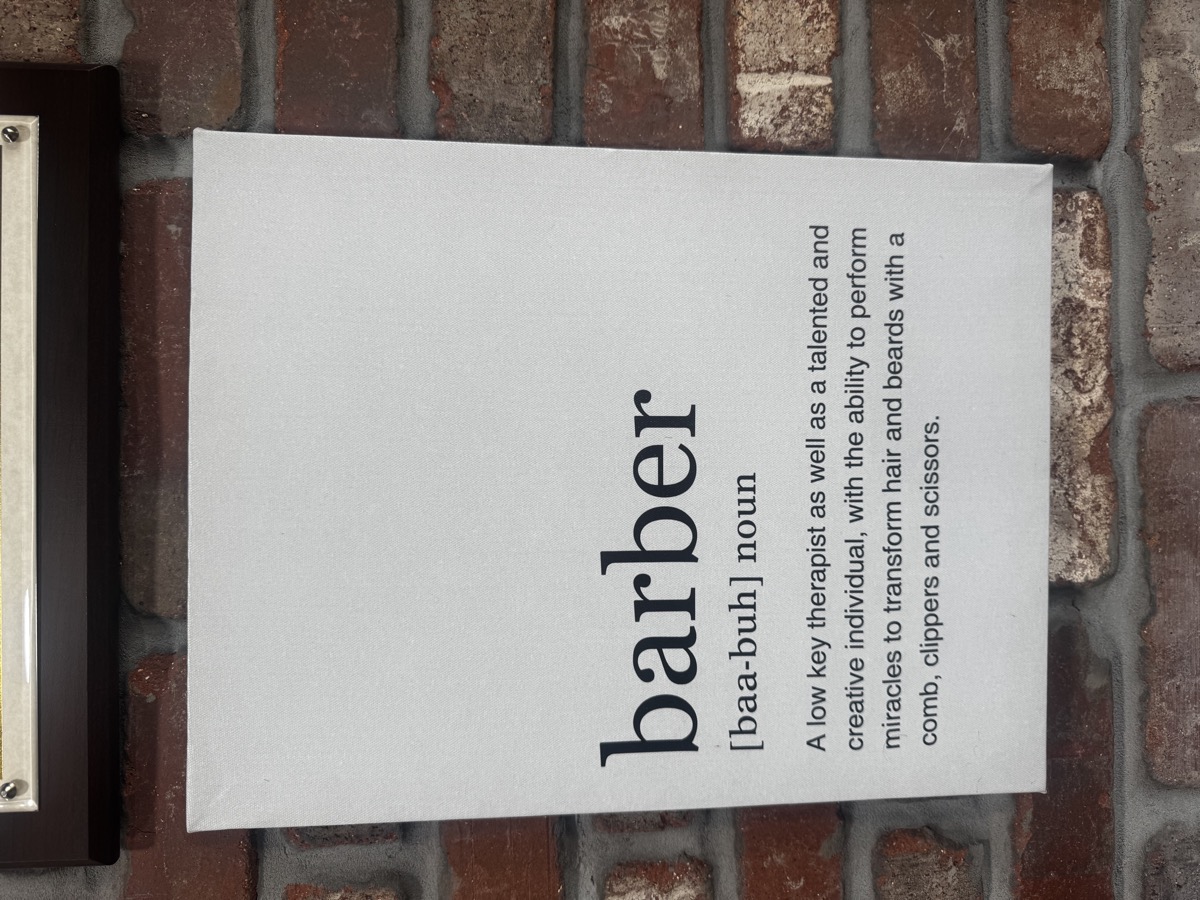 Barber definition canvas art on the exposed brick wall at Bespoke Barber