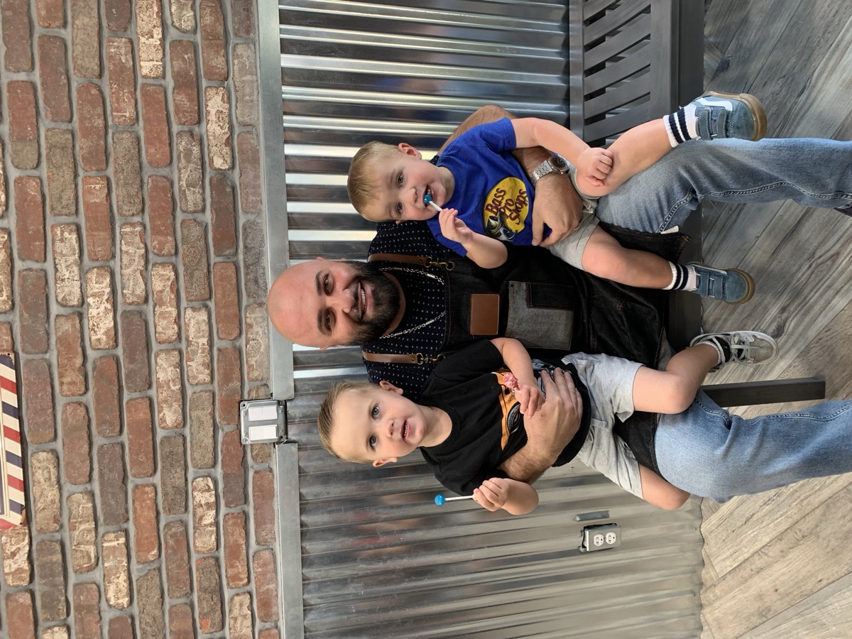 Boris holding two toddlers with lollipops at Bespoke Barber