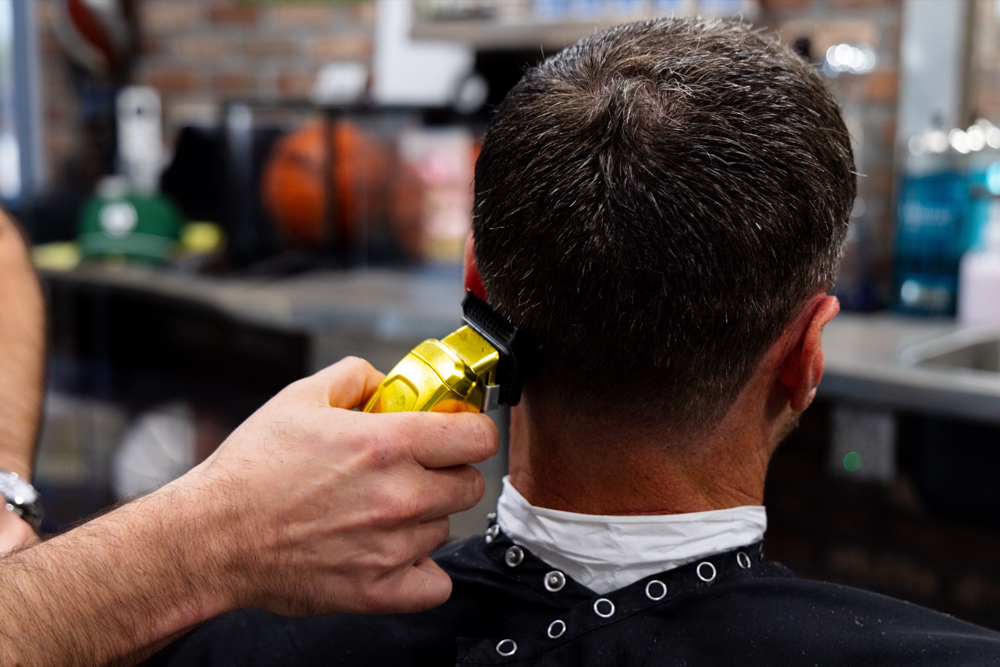 Gold clipper working the back of a client's head at Bespoke Barber
