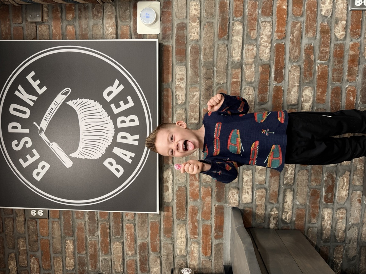 Young boy with lollipop posing with the Bespoke Barber logo