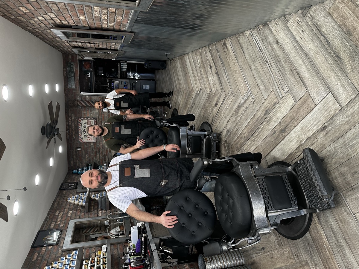 Three barbers standing behind classic barber chairs at Bespoke Barber